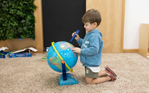 A young boy playing with a globe in his room.