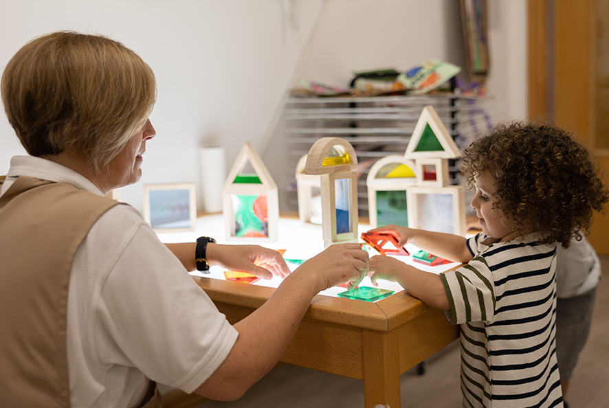 A woman and a child playing with toys at a table.